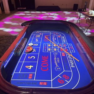 Blue-felt casino craps table with an LED dance floor behind