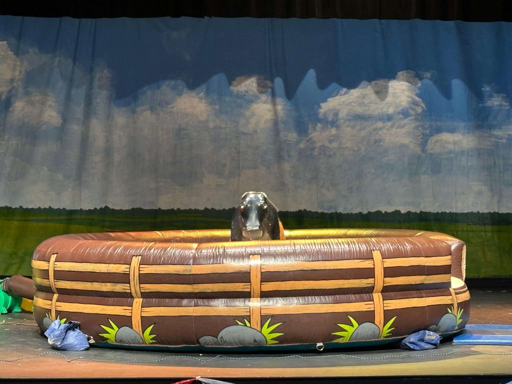 Mechanical bull rig with a cloud-sky backdrop
